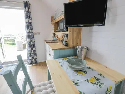 a tiny kitchen with a table and a tv at Laird Lodge 2 in Lockerbie