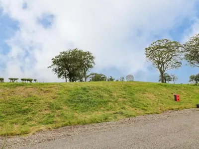 a grassy hill with trees and a red box on it at Laird Lodge 2 in Lockerbie