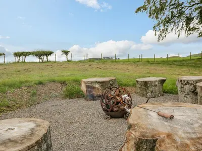 a group of picnic tables and logs with a field at Laird Lodge 2 in Lockerbie
