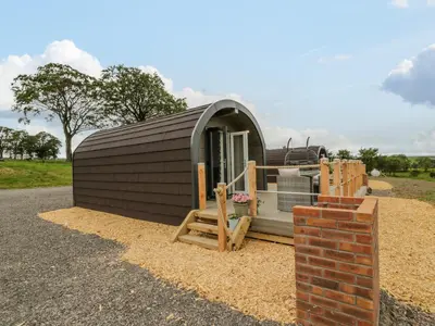a small cabin with a porch and a brick wall at Laird Lodge 2 in Lockerbie