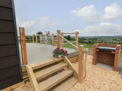 a wooden deck with a bench and flowers on it at Laird Lodge 1 in Lockerbie