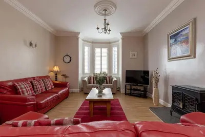 a living room with red couches and a tv at The Knowe in Portpatrick