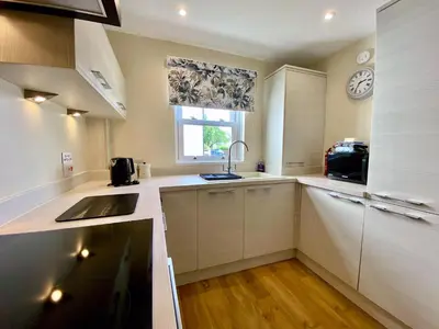 a kitchen with white cabinets and a sink and a window at 8 Howrahs Court, Keswick in Keswick