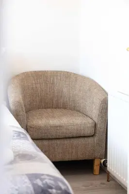 a brown chair sitting in a bedroom next to a bed at 9A Millbrae - Donnini Apartments in Ayr