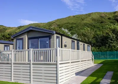 a house with a white fence and a mountain at Bennane Shore Holiday Park in Lendalfoot