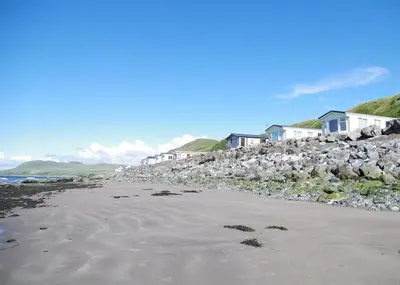 a beach with a bunch of rocks and houses at Bennane Shore Holiday Park in Lendalfoot