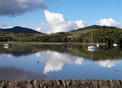 a lake with two boats in the water at Driftwood in Kippford