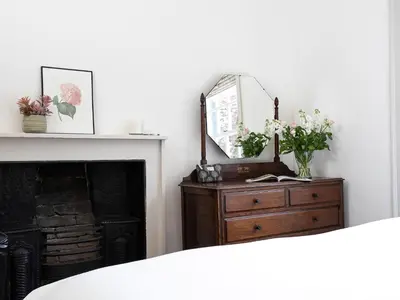 a mirror on top of a dresser next to a fireplace at Thorney How in Ambleside