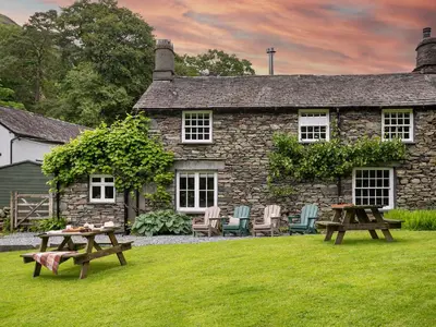 a stone house with two picnic tables in front of it at Little How in Ambleside