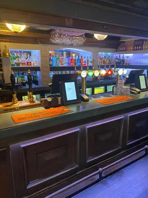 a bar with a counter with a computer on it at George Hotel in Keswick