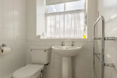 a white bathroom with a toilet and a sink at Dorchester House in Keswick