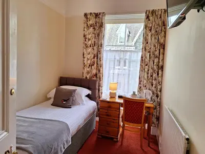 a bedroom with a bed and a desk and a window at Dorchester House in Keswick