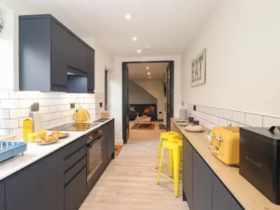 a kitchen with black cabinets and yellow stools at Fran's Nest in Keswick