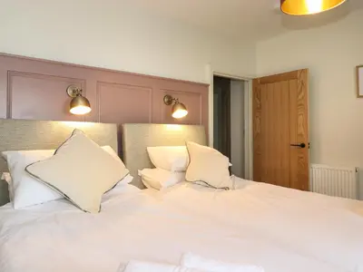 two beds in a bedroom with white sheets and pillows at Fran's Nest in Keswick