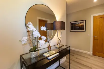 a living room with a glass table and a mirror at Arran View Apartment at Heads of Ayr in Ayr