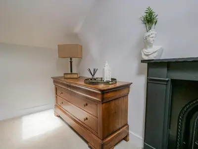 a dresser with a lamp on it next to a fireplace at The Residence in Cleator