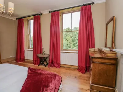 a bedroom with red curtains and a large window at The Residence in Cleator
