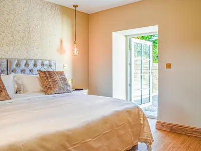 a bedroom with a large bed and a sliding glass door at Bumblebee Cottage-Uk39918 in Ballakinnag