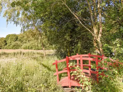 a red bench in the middle of a field at Bumblebee Cottage-Uk39918 in Ballakinnag