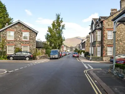 a street in a small town with cars parked at Buttermere Apartment in Keswick