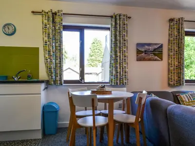 a living room with a table and chairs and a kitchen at Buttermere Apartment in Keswick