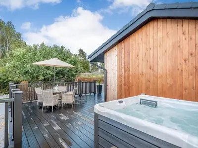 a hot tub on a deck with a table and chairs at Appletree Lodge in Ayr