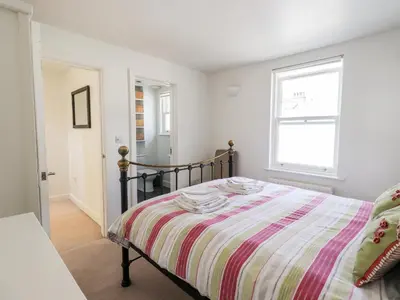 a bedroom with a bed with a striped comforter and a window at Fell Sweep in Keswick