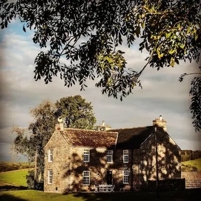 an old stone house sitting on a grass field at Blairinnie in Castle Douglas