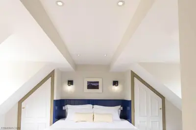 a bedroom with a white bed with blue walls at Culdoach in Castle Douglas