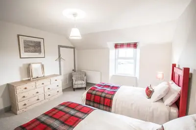 a bedroom with two beds and a dresser at Diamonds Laggan in Castle Douglas