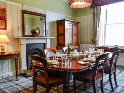 a dining room with a table and chairs and a fireplace at Craigvar House in Castle Douglas