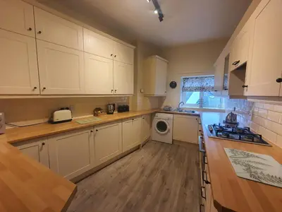 a kitchen with white cabinets and a washer and dryer at Grandy Nook in Keswick