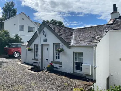 a white house with a red car parked in a driveway at Shelley Cottage in Keswick