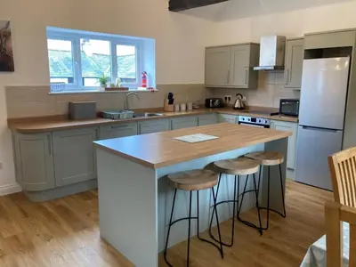a kitchen with a large island with bar stools at Cragside Cottage in Troutbeck