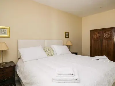 a bedroom with a white bed with two towels on it at Stables Cottage in Langholm
