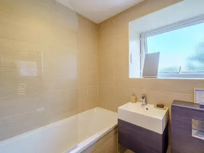 a bathroom with a sink and a bath tub and a window at 1, The Barns in Threlkeld