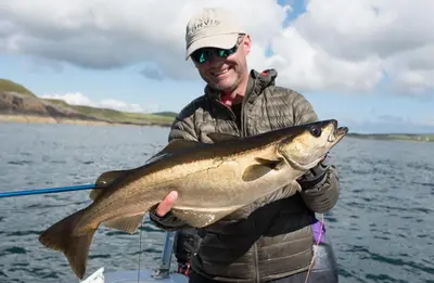 a man holding a large fish on a boat at HV66 - FREE WIFI-3 Bedrooms Indoor Pool Loch Views Fishing Golf Riding Shooting Water Sports 15 Mins Drive To Beaches PASSES NOT INCLUDED Most Activities Will Not Be Available Out Of Season Please Check Before Booking in Newton Stewart
