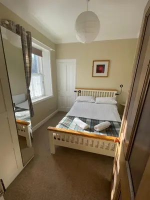 a bedroom with a bed and a large window at Character cottage in centre of Moffat in Moffat