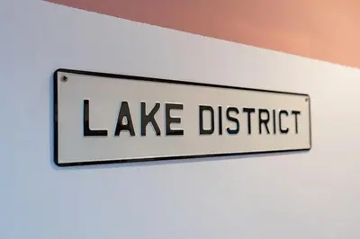 a sign that reads lake district hanging on a wall at Daffodil House in Cockermouth