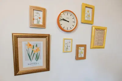 a wall with framed pictures and a clock on it at Daffodil House in Cockermouth