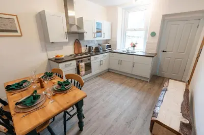 a kitchen with a table and chairs and a kitchen with white cabinets at Daffodil House in Cockermouth