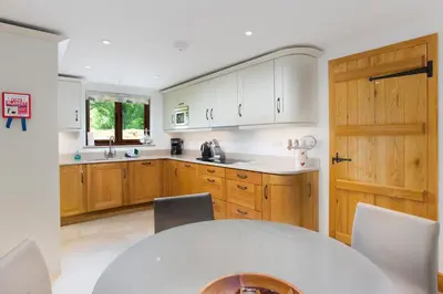 a kitchen with wooden cabinets and a table with chairs at Keiras Cottage in Ambleside