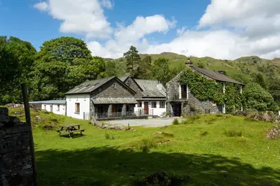 an old house on a hill with a grass field at Keiras Cottage in Ambleside