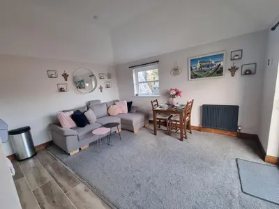 a living room with a couch and a table at The Auld Byre - by the Beach in Dumfries