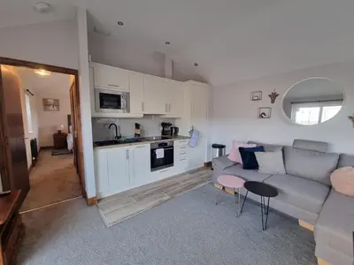 a living room with a couch and a kitchen at The Auld Byre - by the Beach in Dumfries
