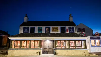 an old building with lights in front of it at The Auld Byre - by the Beach in Dumfries