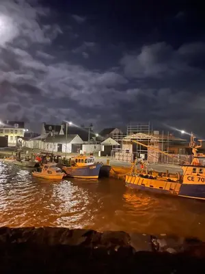 a group of boats docked in the water at night at Immaculate 2-Bed Lodge in Monreith in Newton Stewart