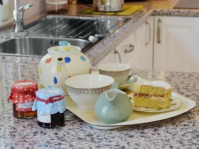 a kitchen counter with a plate of cake and tea pots at Gardener's Cottage in Palnure