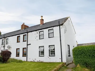 an old white house with a black roof at Coastguard's Cottage in Carsethorn