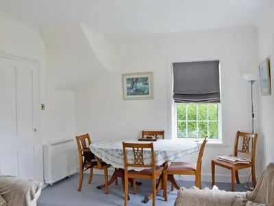 a dining room with a table and chairs and a window at Coastguard's Cottage in Carsethorn